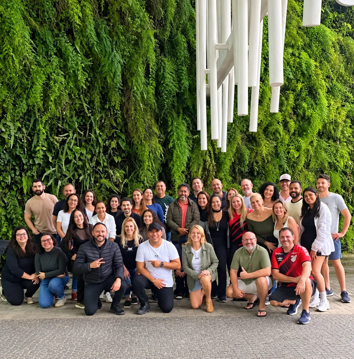 Equipe e participantes do Bora reunidos em frente a um jardim vertical