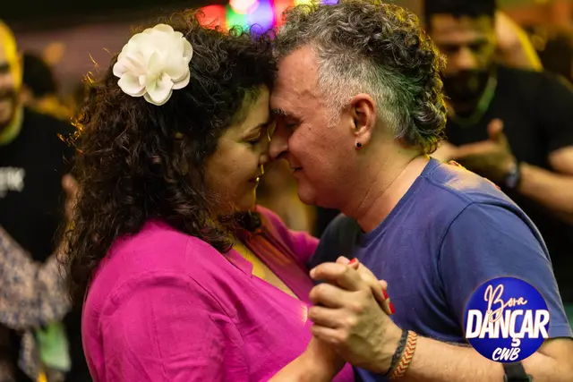 Casal dançando abraçado, ela com uma flor no cabelo