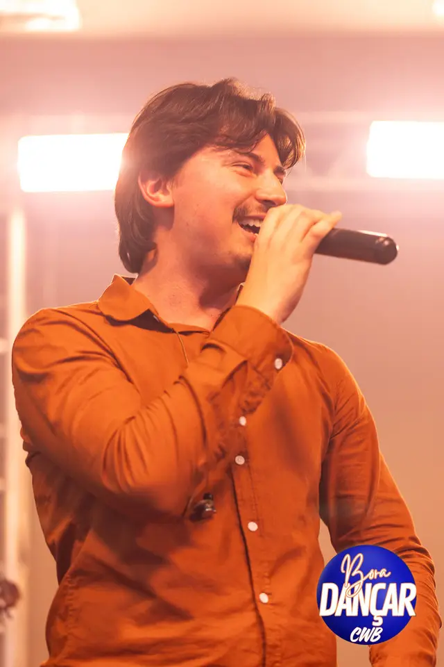 Cantor com camisa laranja no palco